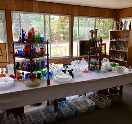 A closer view of the glassware at one end of the long table including the various sets of glassware grouped in boxes under the table.