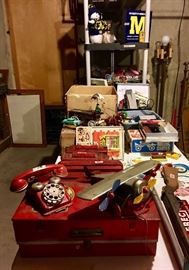 Antique and vintage toys including tin airplane, Lionel train, erector sets, skates, floor lamps, iron horse-drawn fruit vendor, other train sets, photo developing equipment, children's rifle, children's guns and holsters. University of Michigan decorations.
