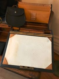 Antique field desk unfolded. Includes ink well (with bottle), pen holder and area for filing items. The inside has wonderful wood finish. Also pictured is a Scottish bag.