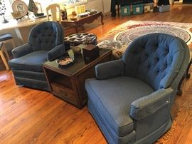pair of button-back Woodmark Original swivel rockers, flanking single drawer burl smoked glass side table 
