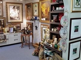 Scented candles, small accent table, brown shelved cabinet, decorative plates, and home decor.