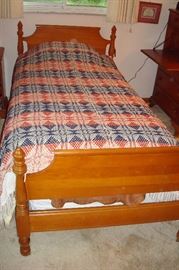 Beech wood single bed covered with antique coverlet.