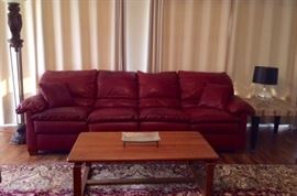 Burgundy leather sofa with large floor lamp, marble-top end table, and Sun Cabinet teak coffee table