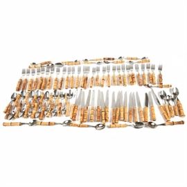 Set of Stainless Steel Flatware with Bamboo Handles: A set of stainless steel flatware with bamboo handles. The set includes ten dinner forks, eighteen smaller forks, ten steak knives, six dinner knives, twenty soup spoons, sixteen regular spoons and two butter spreader knives. They are marked “Made in France – Stainless Steel”.
