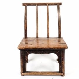 Antique Wooden Chair: An antique primitive wood chair. The short chair is made of painted wood, with mortise and tenon construction. It features a round horizontal top rail and four slightly curved round spindles to the back, with a rectangular wood seat, and straight round legs with scrolled brackets between the front legs finished at the bottom front with a flat foot rest. Not marked.