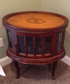 Round Drum or Side Table featuring a beautiful center design, has two doors one opens from the back and one in front, beveled glass panes circle the entire area round this beautiful piece.