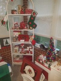 Christmas decorations including stockings, ornament tree, & Lenox Winter Greeting platter. White wicker tall shelf.