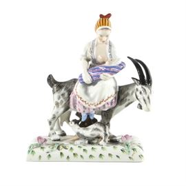 Herend Porcelain Figurine Woman on a Goat Breastfeeding: A Herend porcelain figural group with a breastfeeding mother and goat, Hungary. Two nurturing mothers appear together as the woman exposes her breast to feed her swaddled infant child mounted on a goat whose kid suckles at her teat. Hand painted with rich color and foliage around the base. Marked to the underside with a blue stamp and impressed “HEREND” mark. Inscribed by hand “5708.”