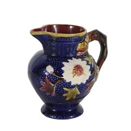 19th-Century English Majolica Pitcher: A 19th-century English Majolica pitcher. Bulbous form body with footed base and hand painted decoration. The handle is in the form a dragon with his head facing to the left and tail wrapping around the bottom. Floriforms adorn both sides of the body with a rich cobalt ground. Marked to the underside" Made in England."