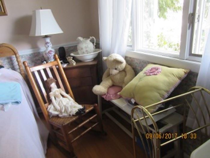 The oak wash stand has 2 drawers and 2 door to open the cabinet. The Maple rocking chair has a woven seat. The early doll is cloth with hand painted face. The pine bench and the towel rack on the right. The Teddy bear and embroidered pillow sit on the bench. 