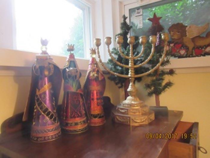 Three wise men with jeweled robes, the Menorahm and two Christmas trees are in the back. 