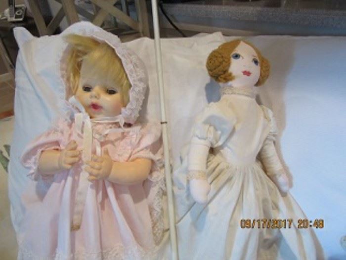 Composition doll on the left is dressed in pink.  The cloth doll on the right has hand painted eyes. 