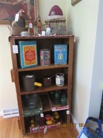 Bird cage on top of this piece which is a dumb waiter, the carved wood couple, and a rooster. the next shelf has early lithographed tins, next shelf has tin sifter, tin pierced candle holder, and crock.  The next shelf has canning jars and lower shelf fruit. 