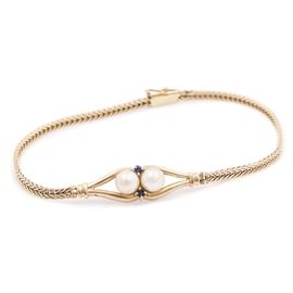 14K Yellow Gold Pearl and Blue Sapphire Bracelet: A 14K yellow gold, cultured pearl, and blue sapphire bracelet. This bracelet features a symmetrical design with open framework leading to a stylized fox tail chain with a bracelet catch clasp.