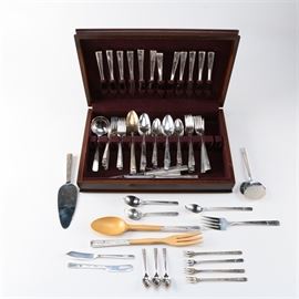 Prestige "Grenoble" Silver Plate Flatware Collection: A large collection of silver plate flatware by Prestige and a Towle sterling spoon. This 126-piece set includes fork cocktail forks, a salad serving set with wooden blades and silver-plated handles, an iced tea spoon, a sugar spoon, a tomato server, a cold meat serving fork, a pie server, a flat handle master butter, a flat handle butter spreader, three demitasse spoons, a gravy ladle, seven table spoon, twenty salad forks, nineteen dinner forks, thirty-two teaspoons, twelve place spoons, and nineteen hollow handle dinner knives with stainless steel blades. These pieces feature the Grenoble pattern and they are each marked “Prestige Plate”. The lot also includes a Towle sterling silver sugar spoon in the Candlelight pattern. The sterling spoon weighs approximately 0.985 ozt.