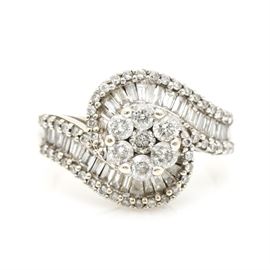 14K White Gold 1.98 CTW Diamond Ring: A 14K White Gold 1.98 ctw diamond ring. This ring features a central cluster of prong set diamonds leading to bypass style shoulders encrusted with flowing channels of diamond baguettes flanked by bead set diamond borders.