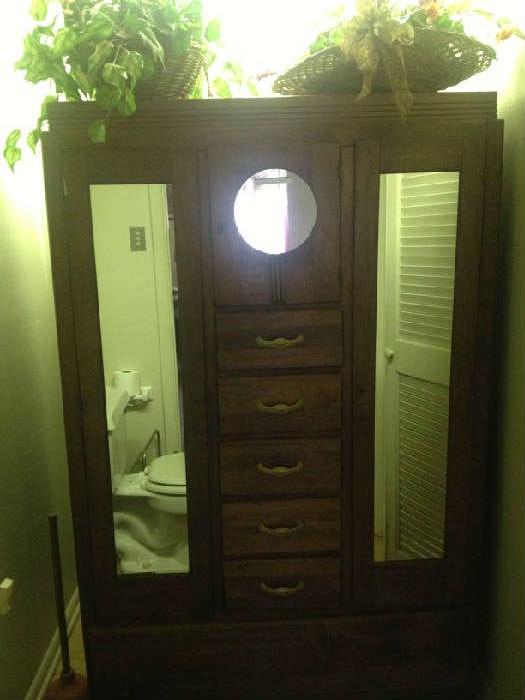 Dark hardwood armor with mirrors on door panels and solid wood drawers. Beautiful antique with lots of character.