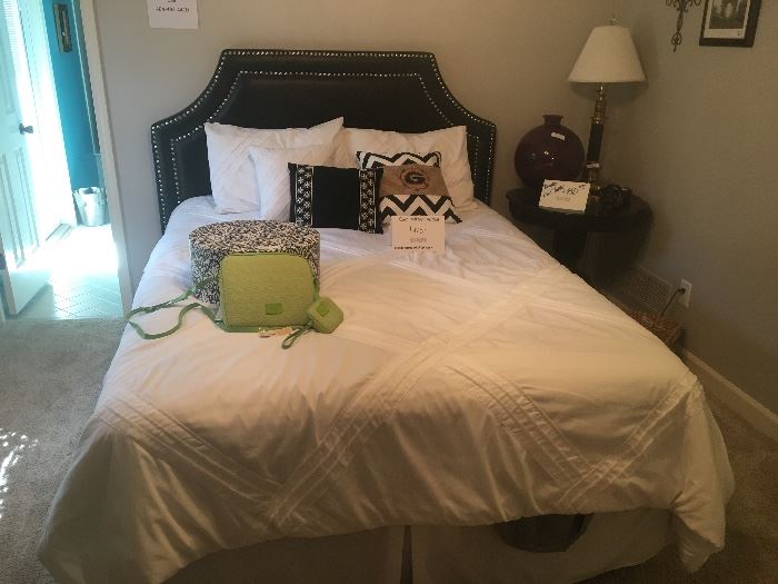 Queen-sized bed with bedding and nailhead headboard