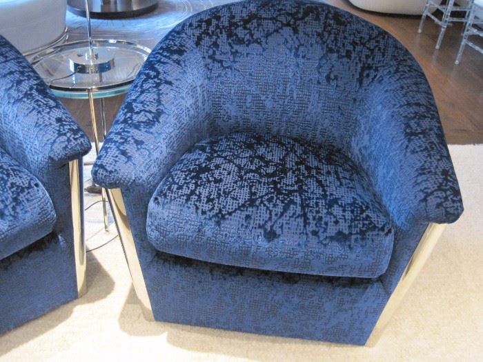 A pair of velvet and chrome swivel armchairs.