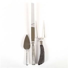 Sterling Silver Serving Pieces: A collection of sterling silver serving pieces. The collection features a pie server, ham slicer by Towle and carving fork with faux antler handle with sterling ferrule. Each piece features a stainless steel blade.