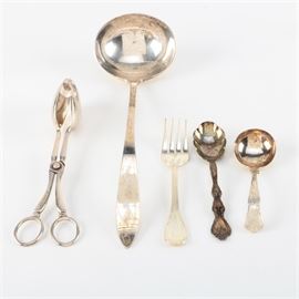 Silver Plate Serving Utensils Featuring International Silver Co.: An assortment of silver plate. This includes five pieces with a pair of salad tongs engraved, “S.G England EPNS A1” as well as a cold meat fork, a sugar spoon by International Silver Co., and a round bowl serving spoon. Items feature markings to the undersides.