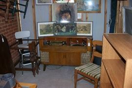 A view of the room in the outer building - which has vintage prints, chairs, sets of chairs, old beds, dining room table - and a wonderful Art Deco radio cabinet
