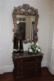 Bernhardt marble-topped chest, Currey & Co. decor obelisks, ornate mirror with distressed gilt finish, faux flower arrangement 
