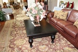Coffee table with flat black finish, faux floral arrangement 
