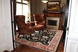 Library: Highland House upholstered chairs and ottoman, area rug, framed oil painting, Trump Home bookshelf, marble-topped side table