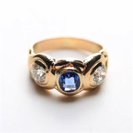 14K Yellow Gold Diamond and Sapphire Three Stone Ring: A 14K yellow gold ring featuring two bezel set old European cut diamonds flanking a center sapphire.
