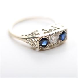 Art Deco 14K White Gold Ring with Diamond and Sapphires: A vintage 14K white gold ring in an Art Deco setting having open pierce work on the under carriage, flush mount with two sapphires and a diamond in a row across the top.