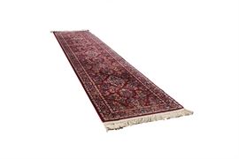 Karastan "Red Sarouk" Wool Carpet Runner: A Karastan Red Sarouk wool carpet runner. It has an overall pattern of floral sprays in colors of navy and Merlot and serged edges. It is made of 100% wool pile of imported wool fiber, and was made in the U.S.A. It has applied cotton fringe and is tagged to the reverse.
This item matches item 17NAS111-103.