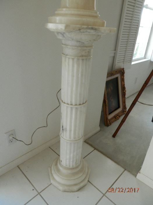 Solid White marble fluted column on which marble lamp sits.