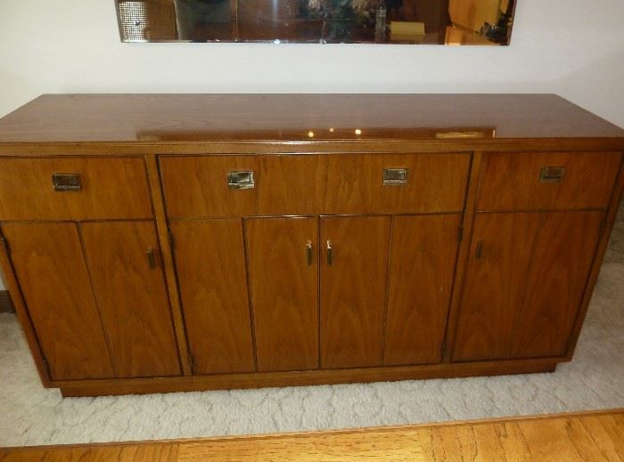 Solid wood Drexel Heritage sideboard, campaign styling, with brass hardware, 3 drawers at top, 2 doors with shelves behind, center double doors with 3 more hidden drawers.
