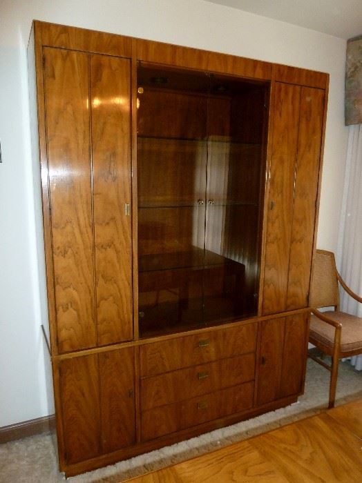 Solid wood Drexel Heritage china cabinet, campaign styling, with brass hardware.  Smoke glass doors, glass shelves, lighted, side doors with shelves behind and 3 large storage drawers.