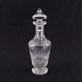 Waterford Maeve Cut Crystal Wine Decanter: A Waterford Maeve cut crystal wine decanter. This decanter features a graduated and faceted stopper, a repeating pattern of elongated cut vertical panels over criss-crossing diamonds, and a circular footed base. The piece has an acid-etched maker’s mark to the underside.