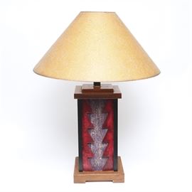 Table Lamp with Wood Base: A southwestern inspired table lamp. This lamp has a painted wood base with a geometric design and red background. It has a cone shaped fabric shade in a tan color.