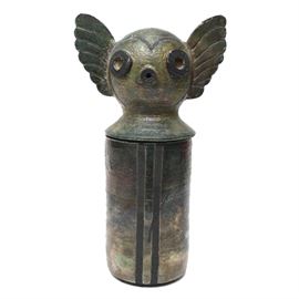 Signed Ceramic Art Canister: A signed ceramic canister. This piece is signed to the base “AR”. It features a whimsical creature with wide eyes and winged ears as the cover and a cylindrical base with four accent vertical stripes. It is glazed in an iridescent green based color.