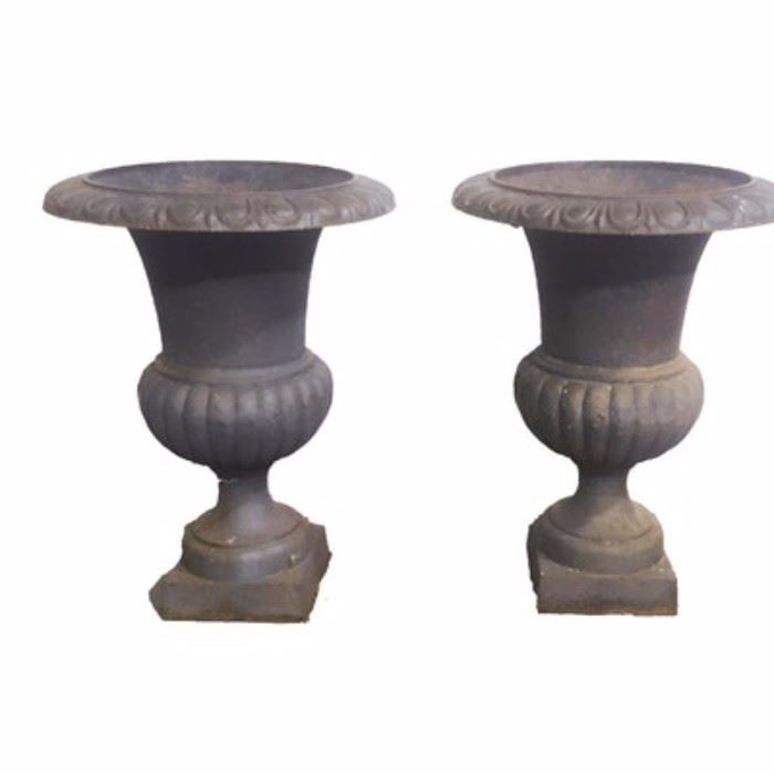 Pair of Black Iron Planters: A pair of cast iron planter urns with a black finish. Includes two urns with raised swag decoration border and reeded detail to the exterior of the bowl. It rests on a square, plinth style base.