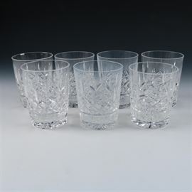 Set of Waterford Lismore Old Fashioned Glasses: A set of Waterford Crystal Lismore old fashioned glasses. Each of the seven glasses have a series of staggered, vertical wedge cuts above a band of cross hatched cuts on a star cut base. They are acid marked “Waterford” to the verso.