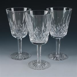 Set of Three Waterford "Lismore" Wine Goblets: A set of three Waterford crystal wine glasses in the Lismore pattern. Each bowl features vertical and diamond cuts atop a faceted stem with a round base accented by a cut star design. All feature an acid-etched Waterford hallmark to the underside.