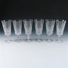 Waterford Crystal "Lismore" Ice Tea Glasses: A set of six Waterford Lismore crystal ice tea glasses. The pattern features intersecting vertical cuts to the body, a faceted stem, and a starburst design to the base. Each piece is marked “Waterford” to the base.