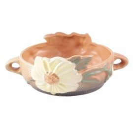 Roseville Floral Motif Double Handled Ceramic Planter: A Roseville floral motif double handled ceramic planter. This pink ceramic planter features a round rim with flared white peony floral accents and green leaf motif and has dual handles to the body. Planter is marked to the underside, “Roseville-428-6”.
