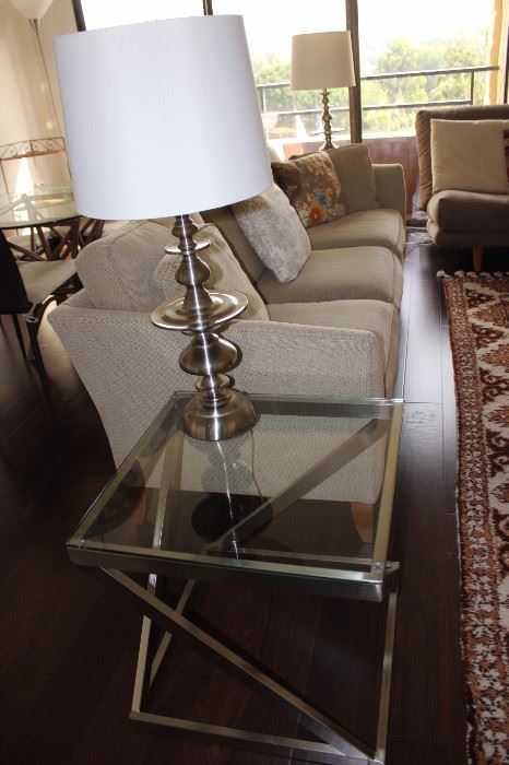 One of two matching glass and chrome end tables and one of two matching table lamps.