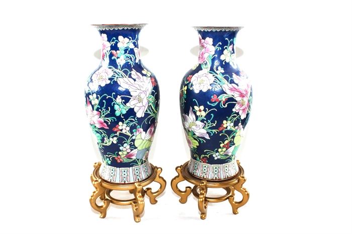 Pair of Large Chinese Vases: A pair of large matching Chinese vases. These decor pieces have an all-over floral and foliate design, in hues of blue, pink, green and yellow. Both come with wooden bases.