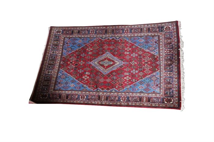 Large Persian Rug: A large Persian rug with an all-over floral and foliate design on a crimson background; further accented in hues of blue, green, beige, cream and brown.