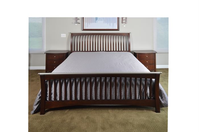 King Size Slatted Sleigh Bed with Nightstand Pair by Thomasville: A king size sleigh bed and pair of matching nightstands by Thomasville. The bed has a wooden frame with vertical slats to the headboard and footboard, which are each topped by a silver tone metal rod capped at the ends with ball finials; they rest on block feet and are connected by plain side rails. The matching nightstands have a slightly bowed front and three stacked drawers with silver tone knobs on block feet; they are marked “Thomasville” to the drawer interiors.