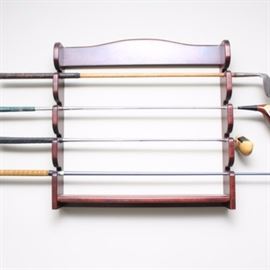 Display Rack With Callaway Golf Clubs: A wooden golf club display rack. This wooden shelf features room for four golf clubs and hangs on the wall. Four clubs featuring Callaway are included.