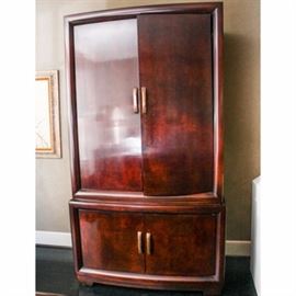 Contemporary Wood Entertainment Center: A contemporary wood entertainment cabinet. Behind the glossy double doors, this cabinet features open cabinet atop dual doors with shelving. Brass hardware throughout.