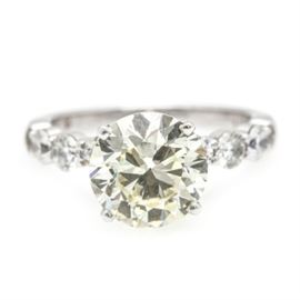 14K White Gold 3.68 CTW Diamond Ring: A 14K white gold 3.68 ctw diamond ring. This ring comprises a 3.01 ct center round diamond, mounted in a four prong peg head setting between diamond embellished shoulders.